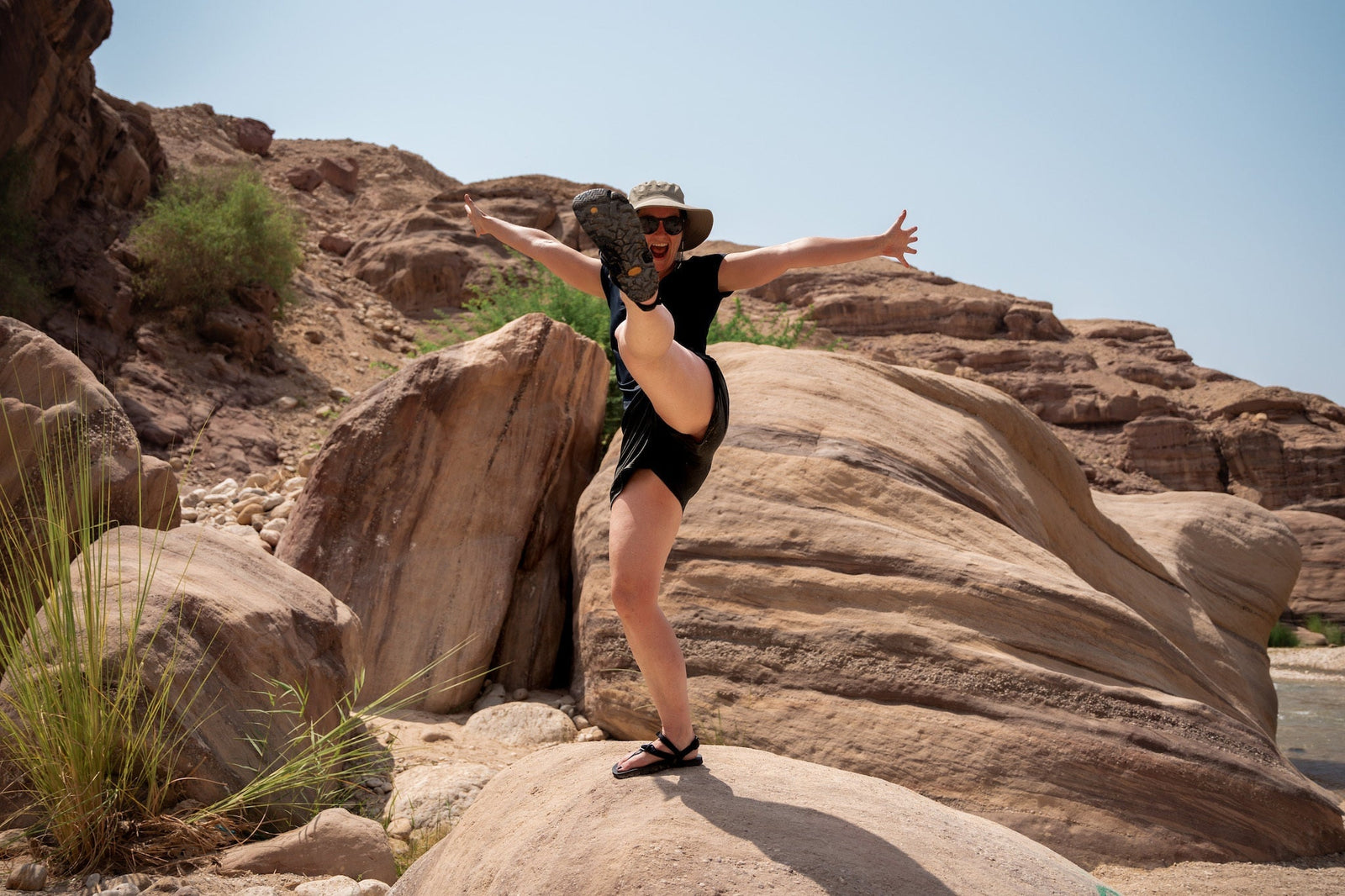 A woman kicks her LUNA out in front of her as she stands on a rock.