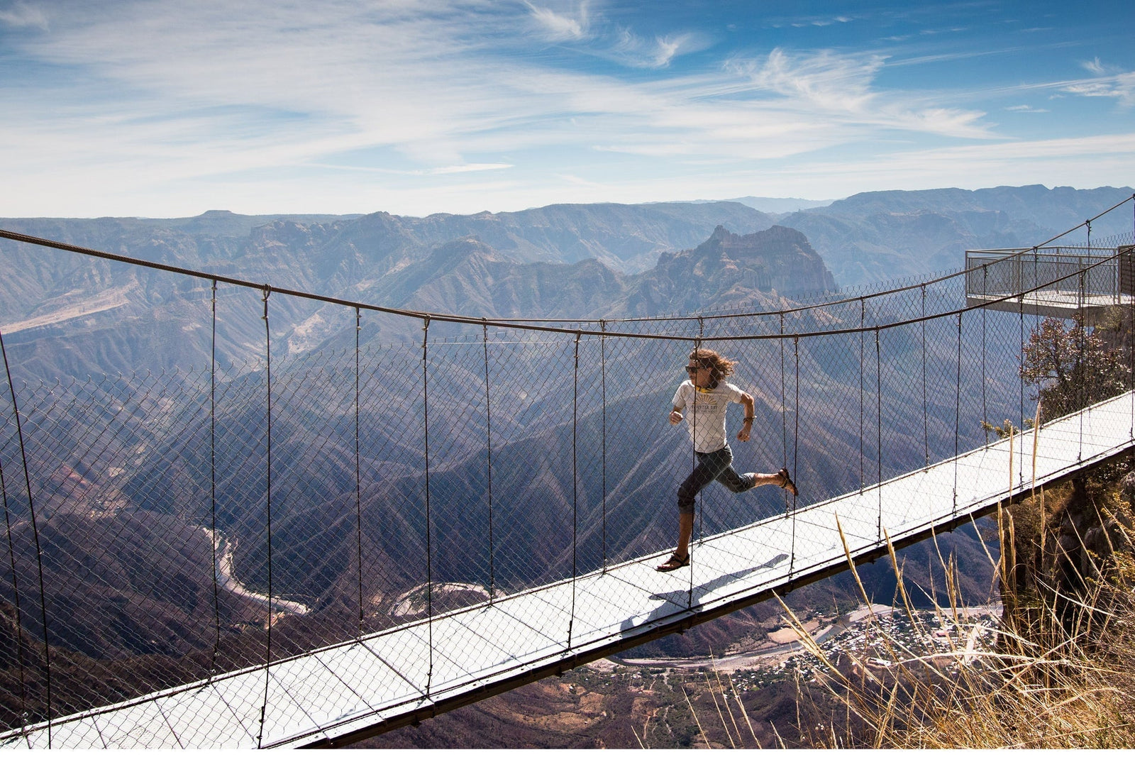 A human runs across a bridge in the mountains