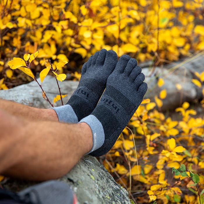 Injinji Toe Socks - Trail Midweight - Granite - crouched on rock in autumn brush