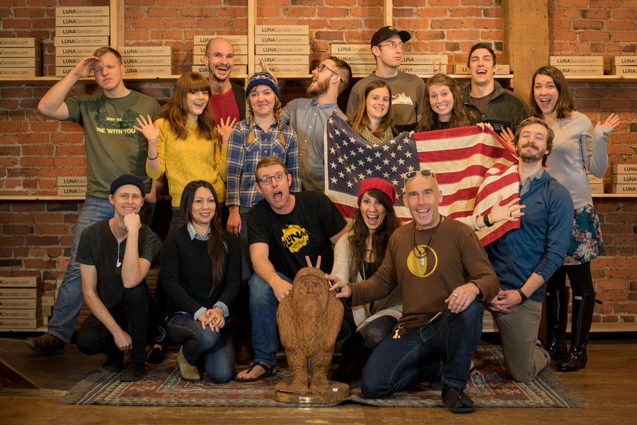 The LUNA team gathered in the Seattle shop in 2017 with a United States flag and the carved American Made Outdoor Gear Award trophy, boxes stacked on the shelves behind them.