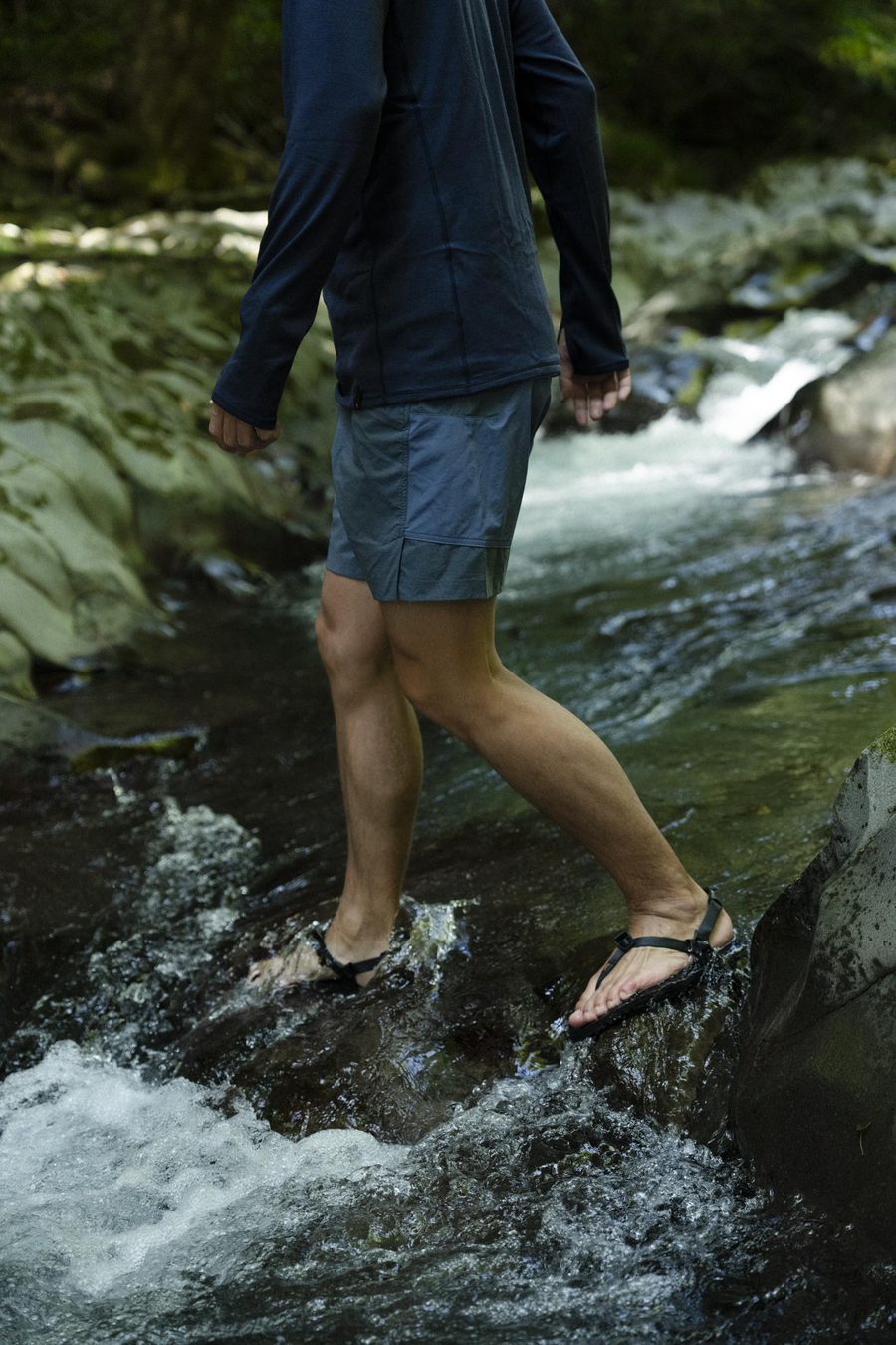 Legs in LUNAs stepping across a rushing creek, water breaking white over the rocks.